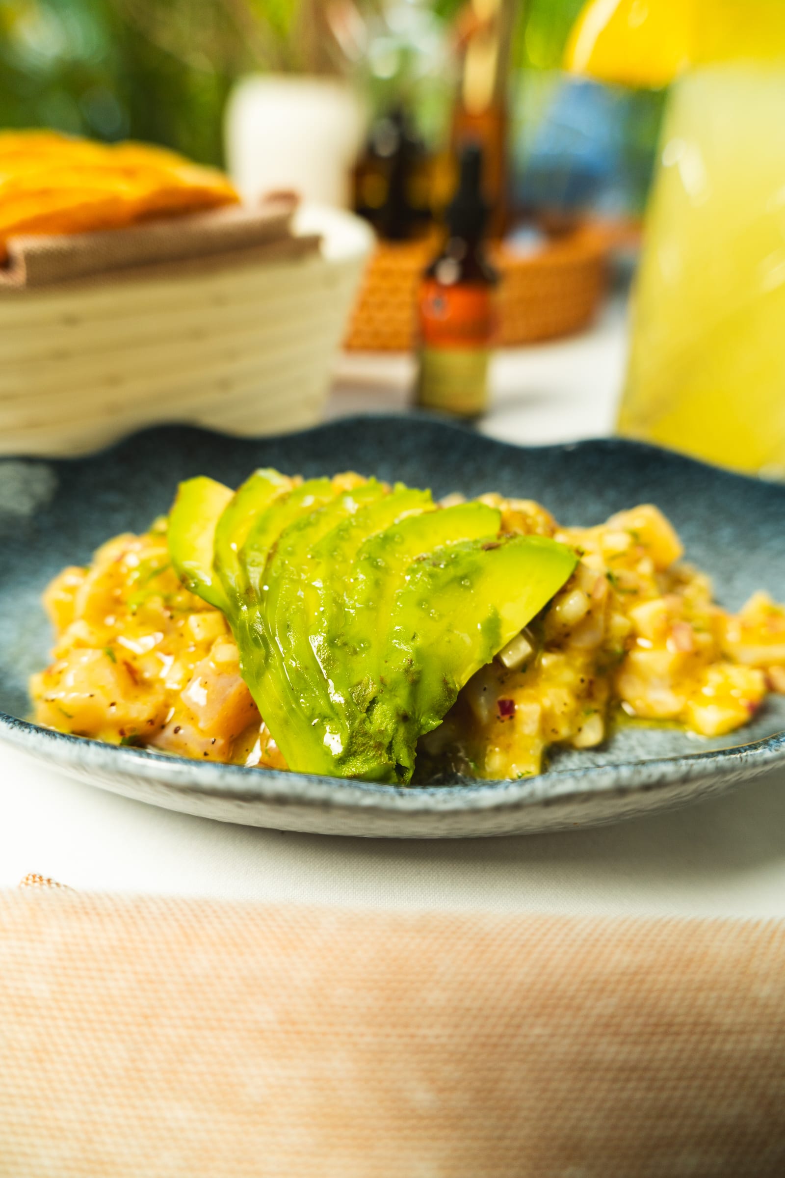 Aguachile con abanico de aguacate en aderezo amarillo en plato azul con forma de pez